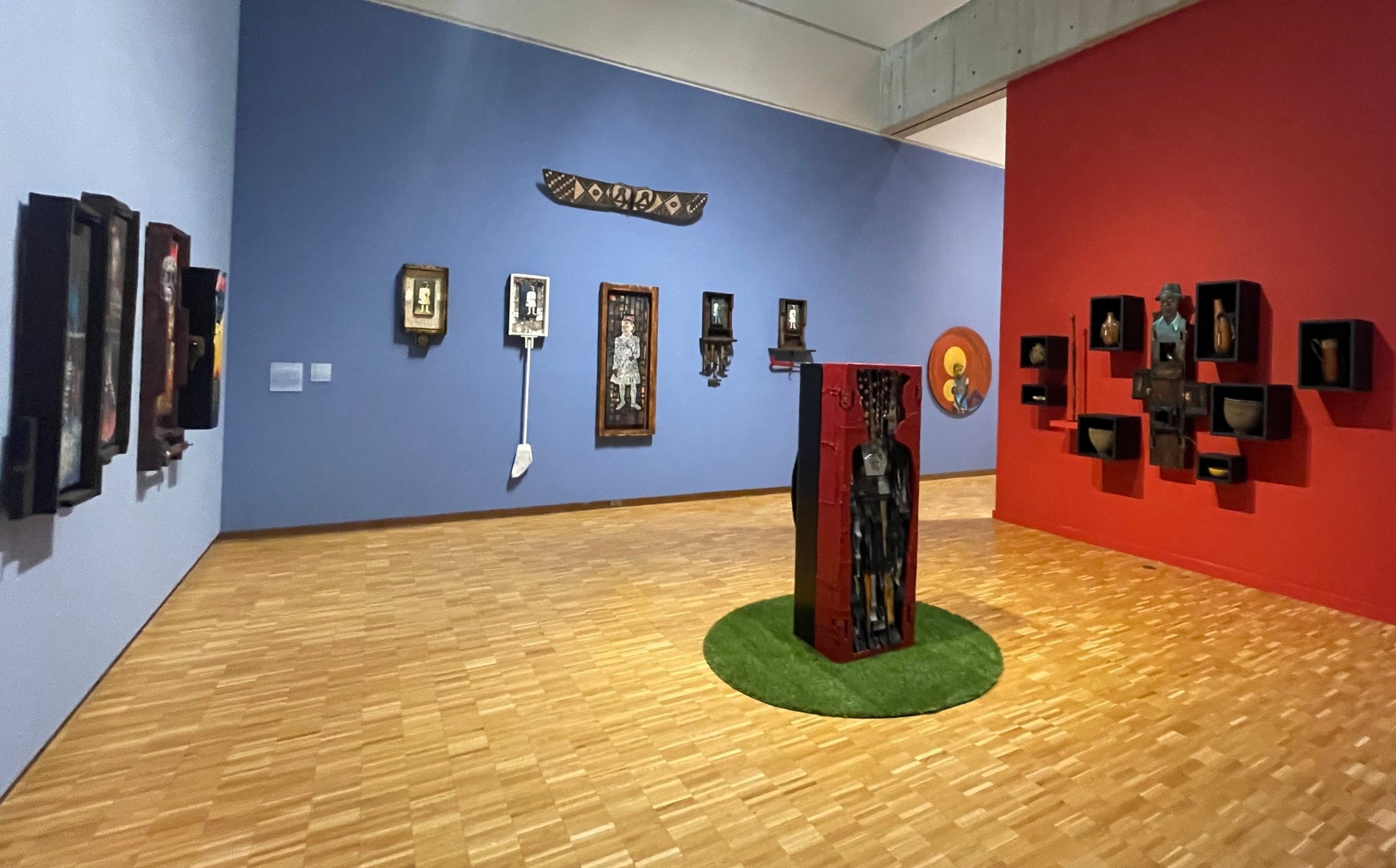 Thresholds installation at the Haggerty Museum of Art: carved assemblages on blue and red walls, with a red and black standing sculpture at center